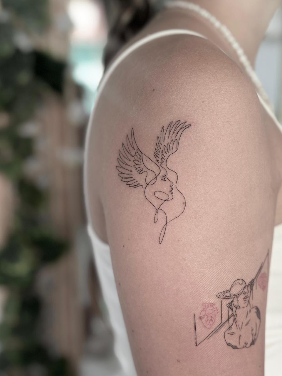 Minimalist shoulder winged figure fine line tattoo